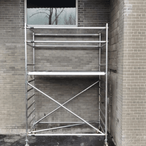 A metal scaffolding is in front of a brick building.