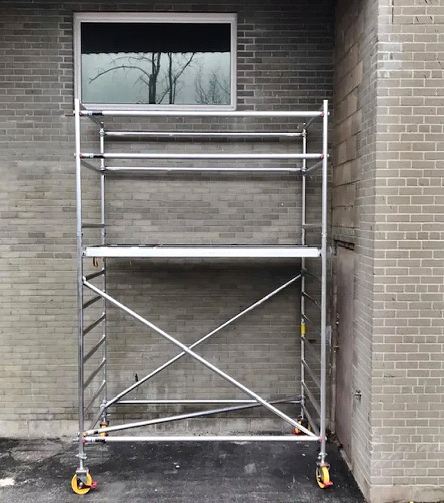 A metal scaffolding is in front of a brick building.