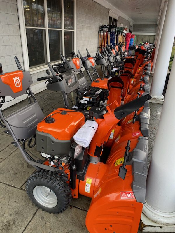A row of orange snowblowers are lined up.