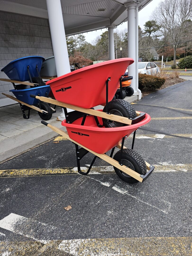 A red wheelbarrow sitting in the middle of a parking lot.